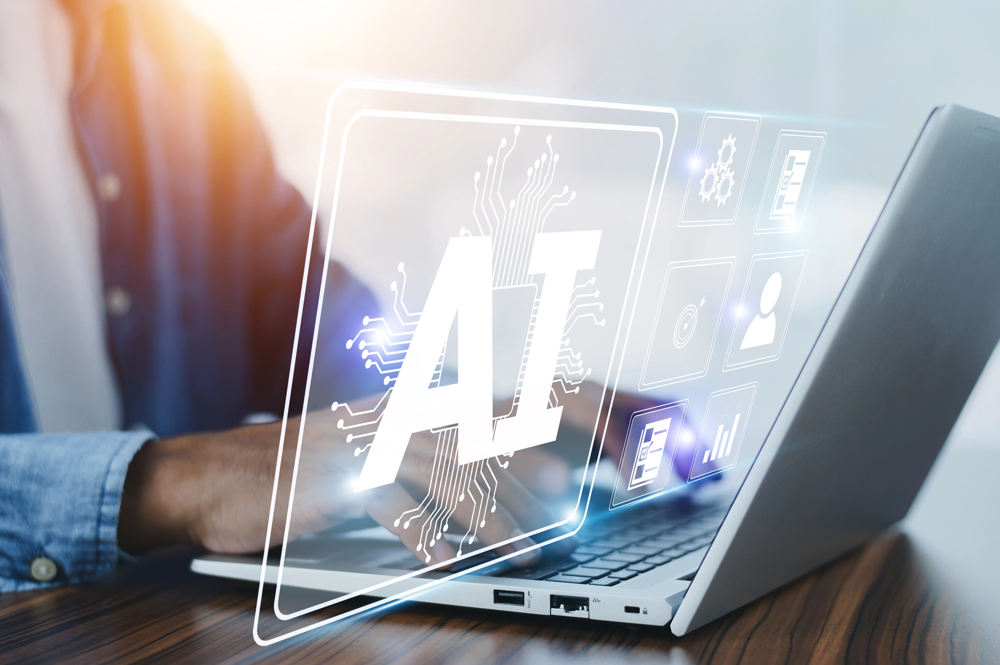 Mann sitzt an einem Laptop, auf dem BIld schwebende Symbole aus dem AI-Bereich
